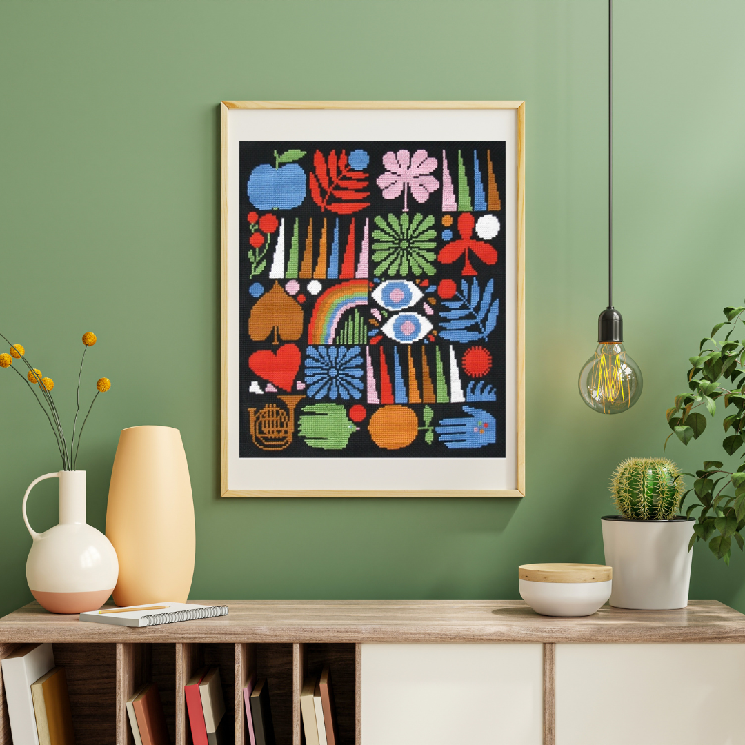 Framed Joyful Grid cross stitch displayed on a shelf in a contemporary living room with decorative styling.