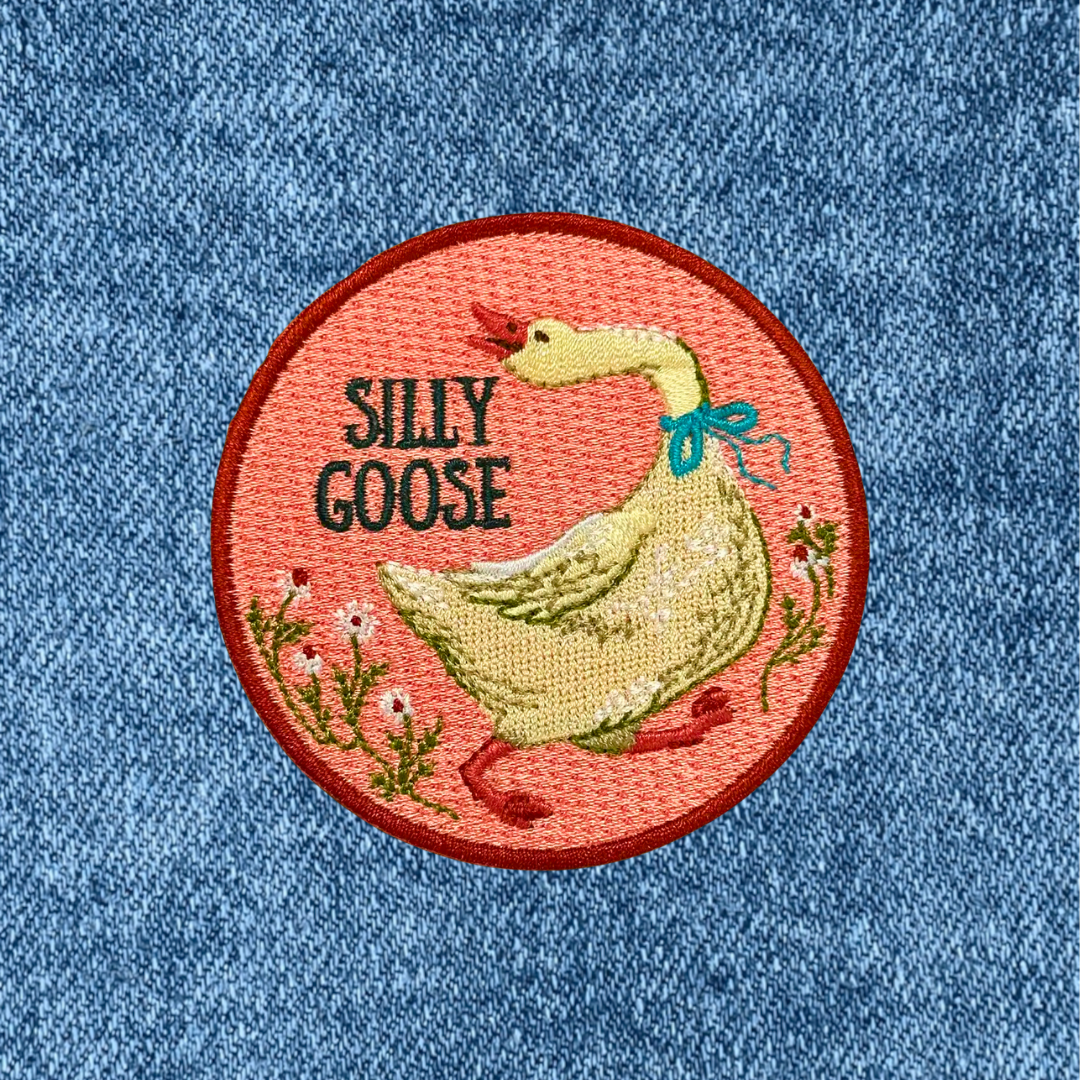 Silly Goose iron on embroidered patch by Anna Seed Art applied to blue denim fabric.