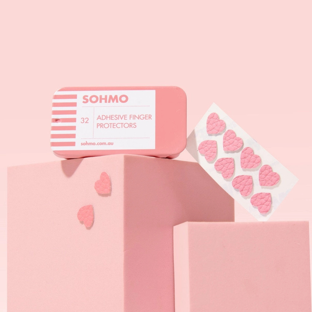 SOHMO Adhesive Thimble Pads in pink metal tin with lid removed, showing the individual adhesive pads and pink packaging.