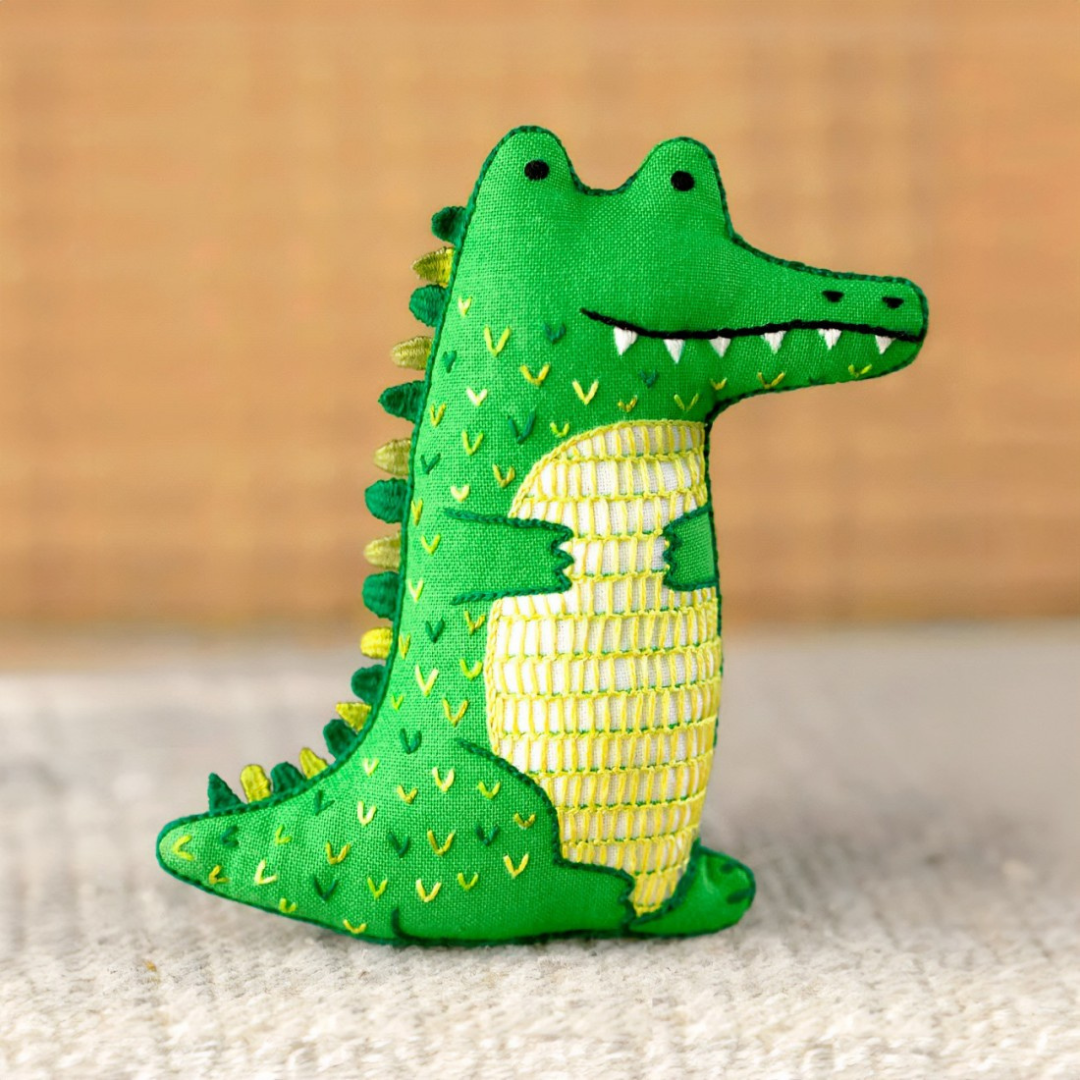 Finished alligator embroidery kit displayed on a wooden surface