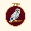 Finished Snowy Owl Mini Embroidery Kit by Paraffle displayed in a wooden embroidery hoop