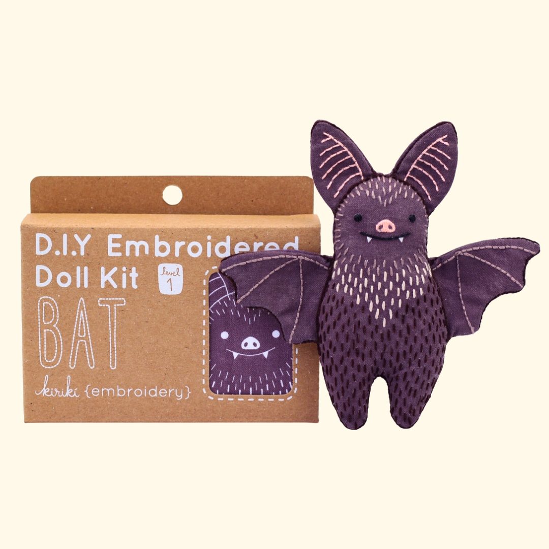 Bat Embroidery Kit by Kiriki Press shown with the completed embroidered doll and packaging.