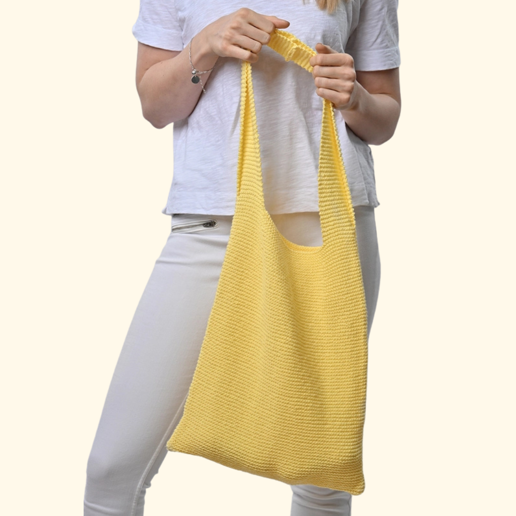 Model carrying the completed knitted beach bag made with the Wool Couture Beach Bag Knitting Kit.