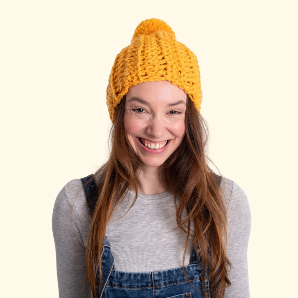 Model wearing the completed crocheted beanie showcasing the classic pom pom design.