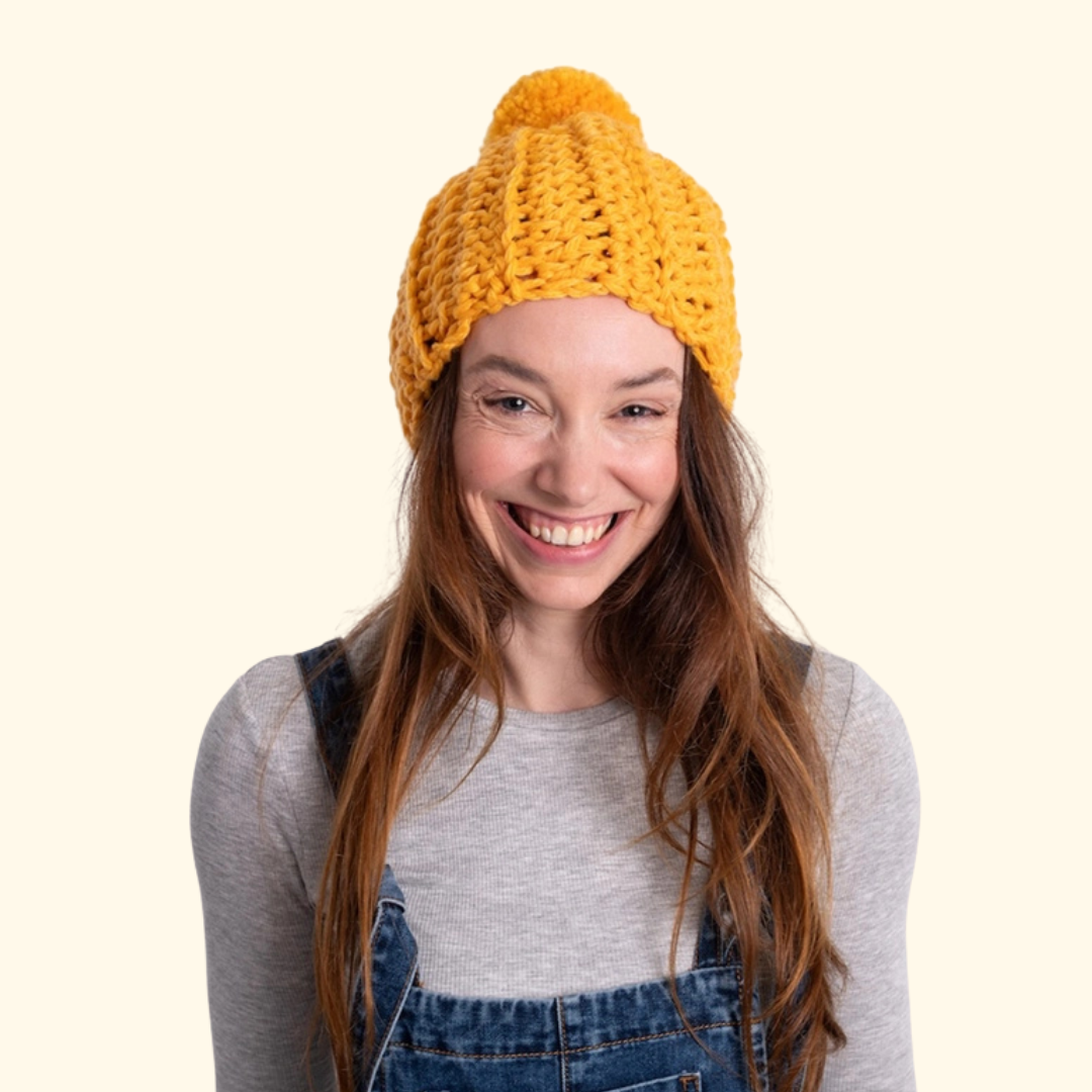 Model wearing the completed crocheted beanie showcasing the classic pom pom design.
