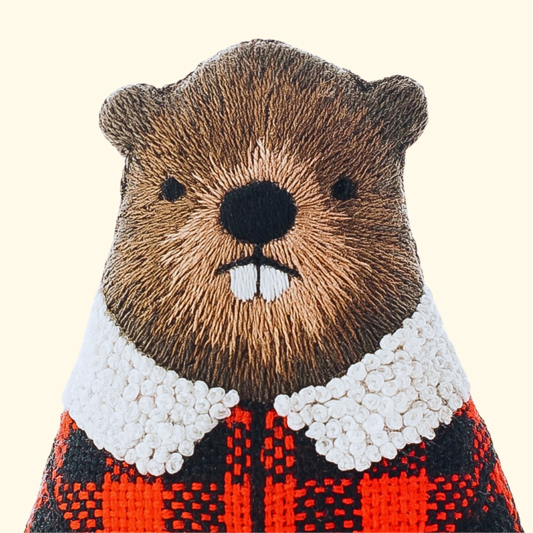 Close-up of the finished beaver embroidery doll with textured brown fur and a plaid jacket.