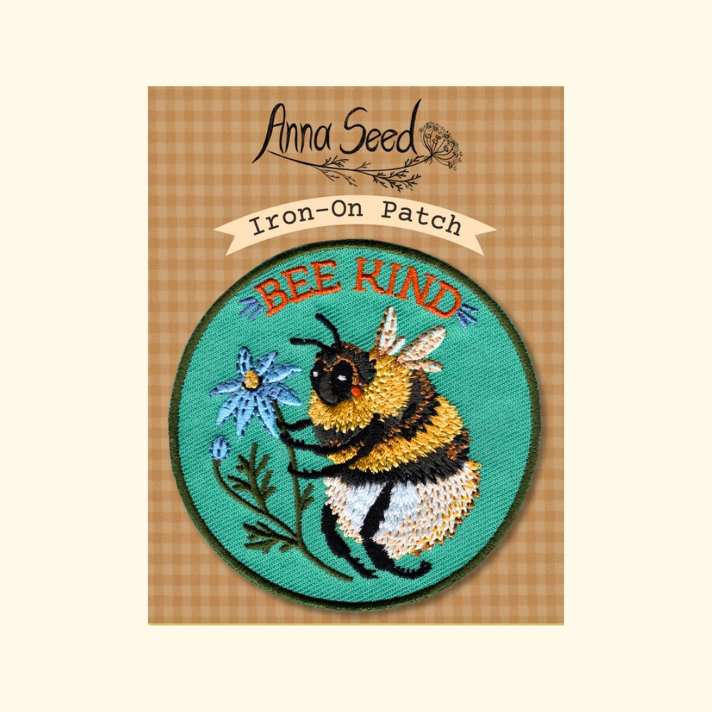 Packaged Bee Kind embroidered iron on patch by Anna Seed Art displayed on its backing card.