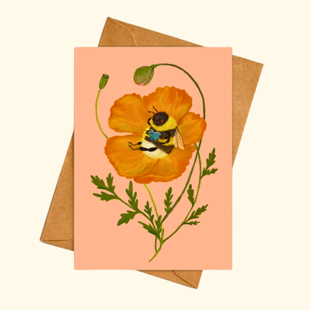 Beebliophile greeting card shown with a matching kraft envelope, featuring a charming bee reading a book while resting inside a vibrant orange poppy.