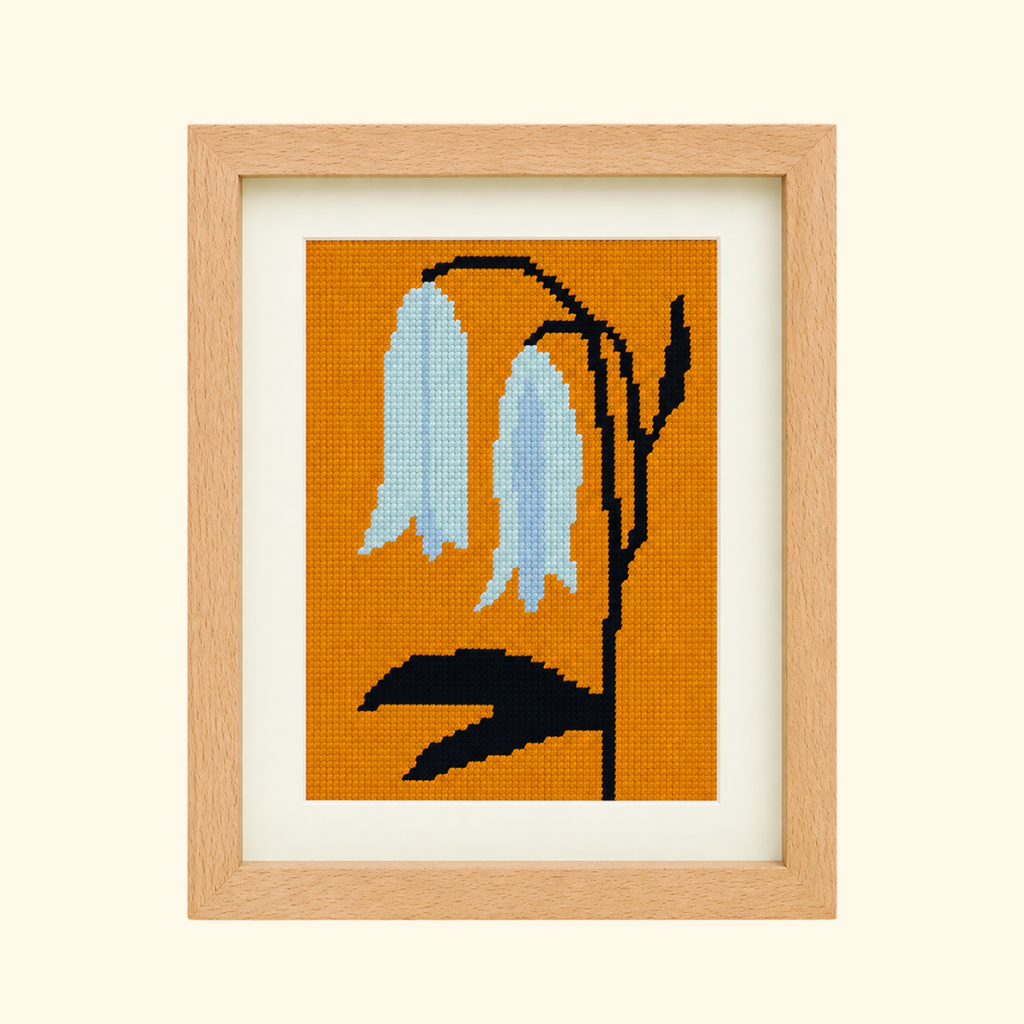 Bellwort Needlepoint Kit by Unwind Studio with finished blue floral design framed in timber