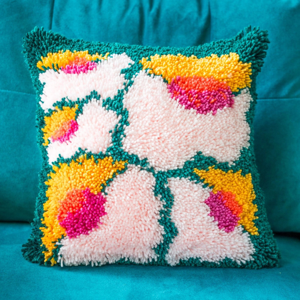 Completed Bloomin Lovely latch hook cushion displayed on a sofa, showcasing the finished textured design.