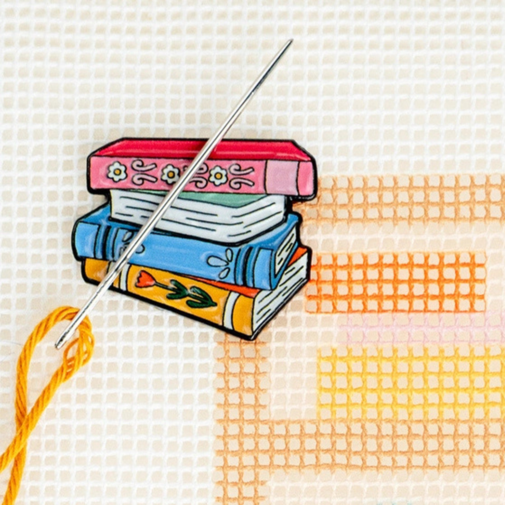 Book Lovers magnetic needle minder holding a needle securely on a needlepoint canvas.