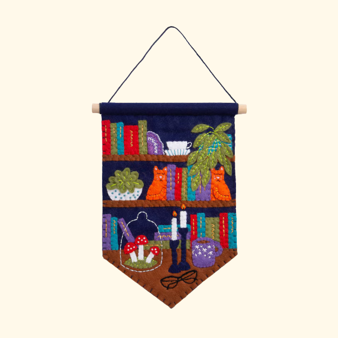 Felt wall hanging featuring a colourful bookshelf filled with books, plants and decorative objects