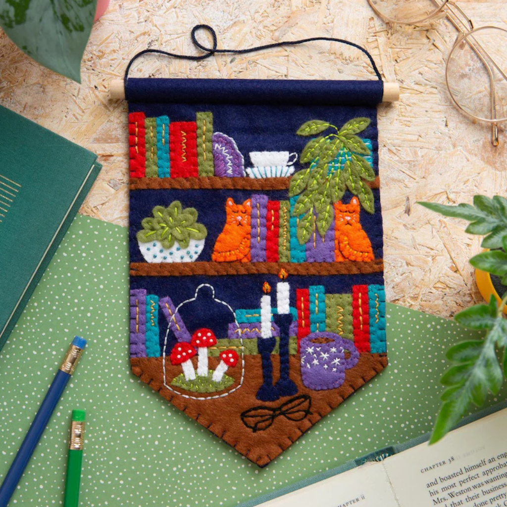 Completed Book Nook felt wall hanging displayed on a craft table with pencils and a notebook