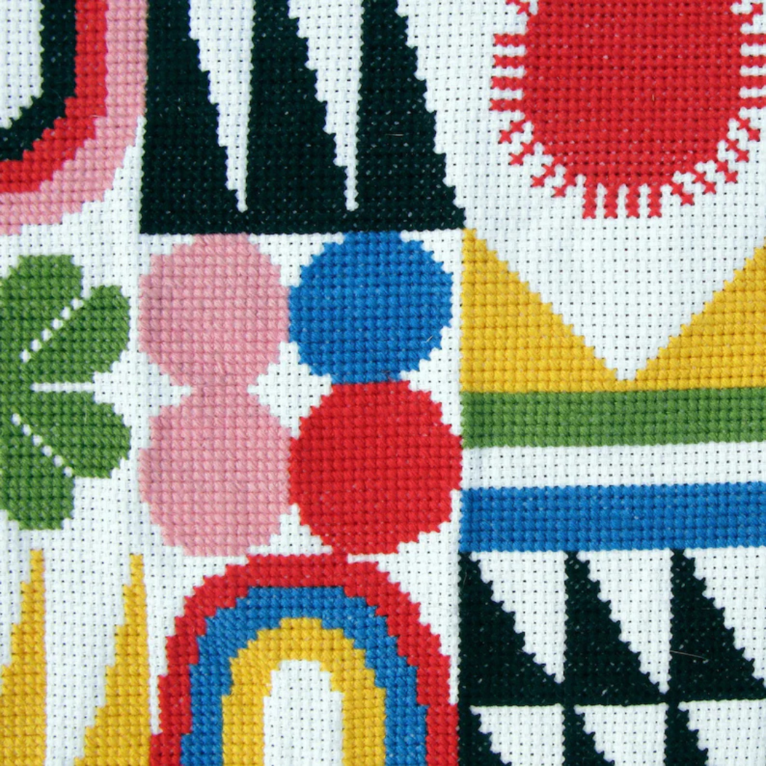 Close-up of the Brightside Grid cross stitch design featuring colourful geometric shapes, flowers and rainbow motifs.