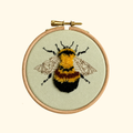 Completed Bumblebee Mini Embroidery Kit by Nest Embirdery featuring a fluffy yellow and black bee in a wooden hoop.