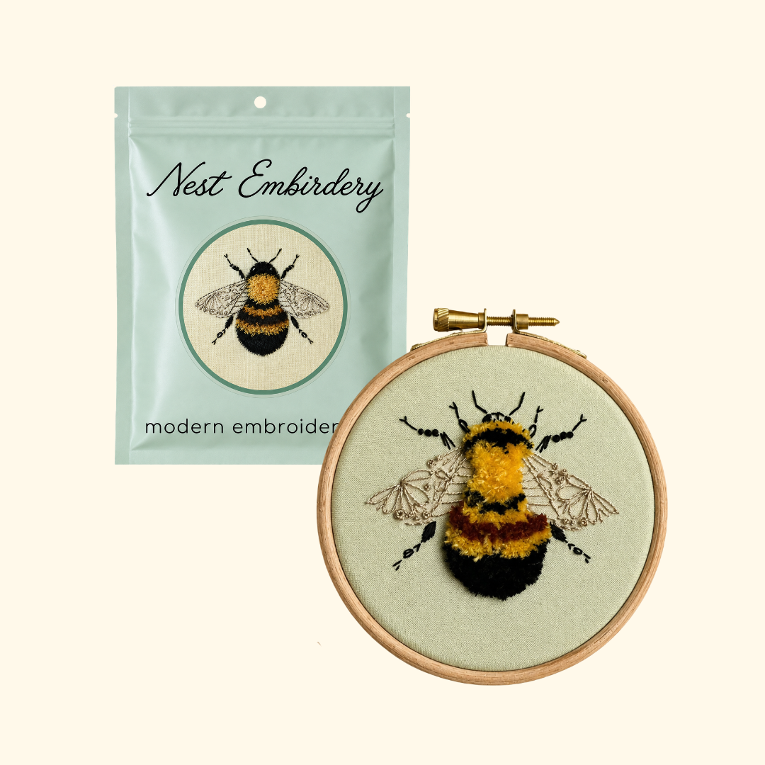 Nest Embirdery Bumblebee Mini Embroidery Kit packaging displayed alongside the completed bee embroidery in its wooden hoop.