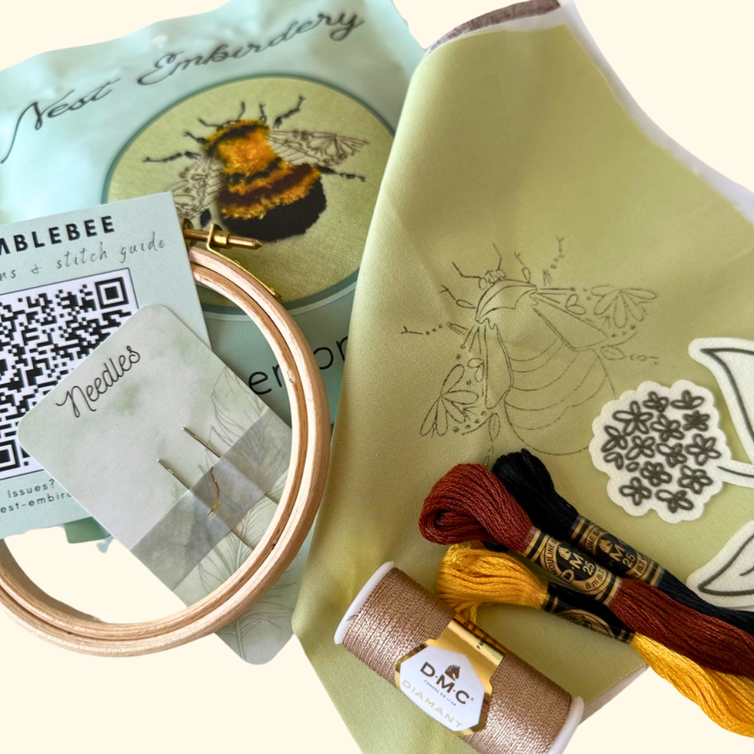 Close-up of the Bumblebee Mini Embroidery Kit by Nest Embirdery with embroidery threads and wooden hoop.