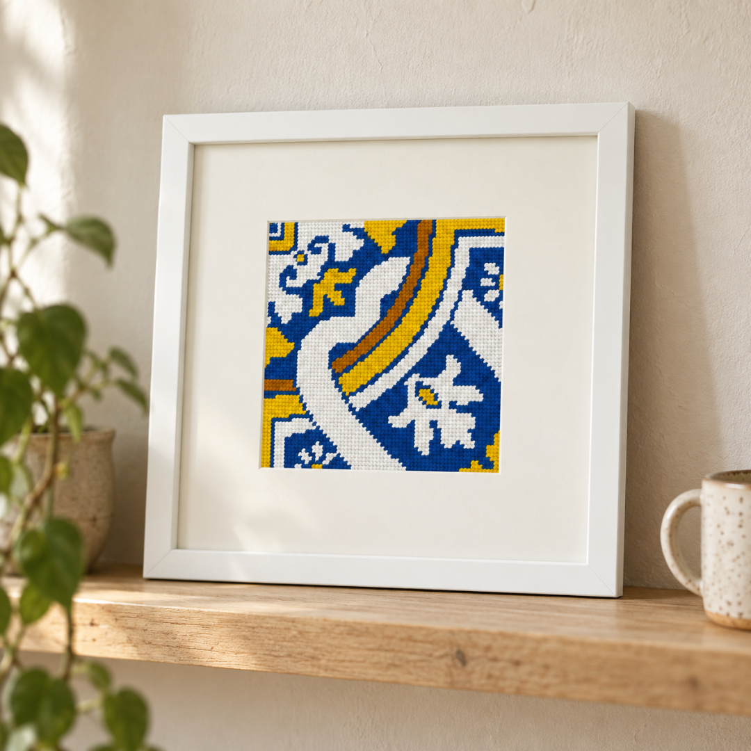 Finished Cedofeita Portuguese tile needlepoint displayed in a cream frame on a wooden shelf.