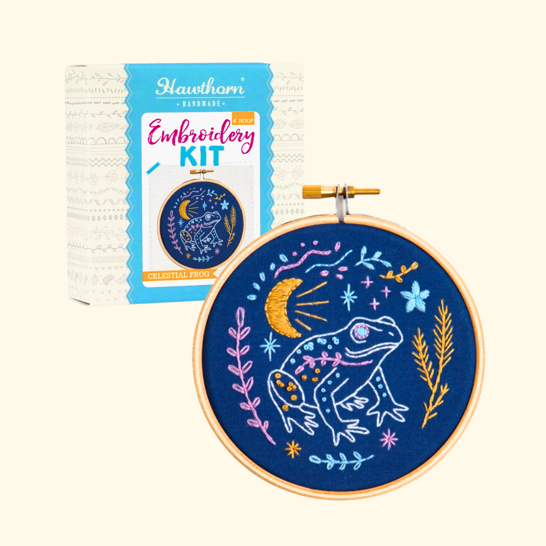 Celestial Frog Mini Embroidery Kit by Hawthorn Handmade with the presentation box beside the finished embroidery hoop.
