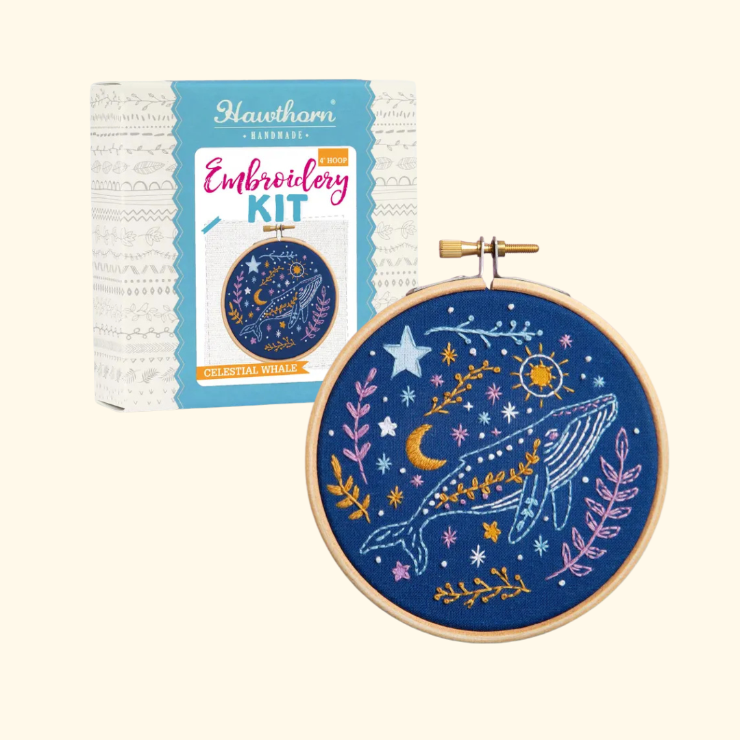Celestial Whale Mini Embroidery Kit box displayed beside the finished whale embroidery hoop design.