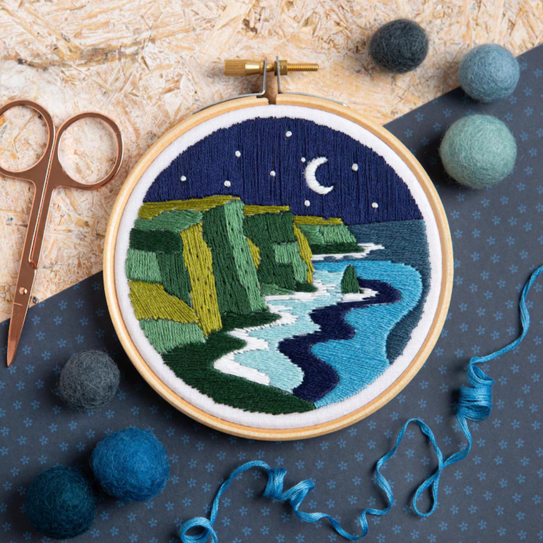 Celtic Cliffs Mini Embroidery Kit by Hawthorn Handmade styled with embroidery scissors, thread and crafting accessories.