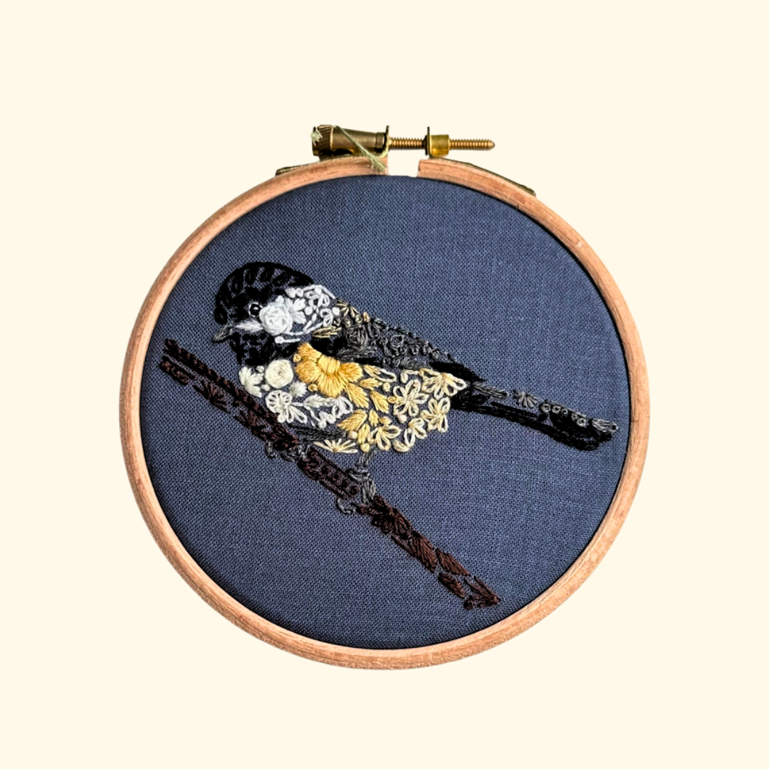 Completed Chickadee Mini Embroidery Kit by Nest Embirdery featuring a fluffy black-capped chickadee stitched onto navy fabric.