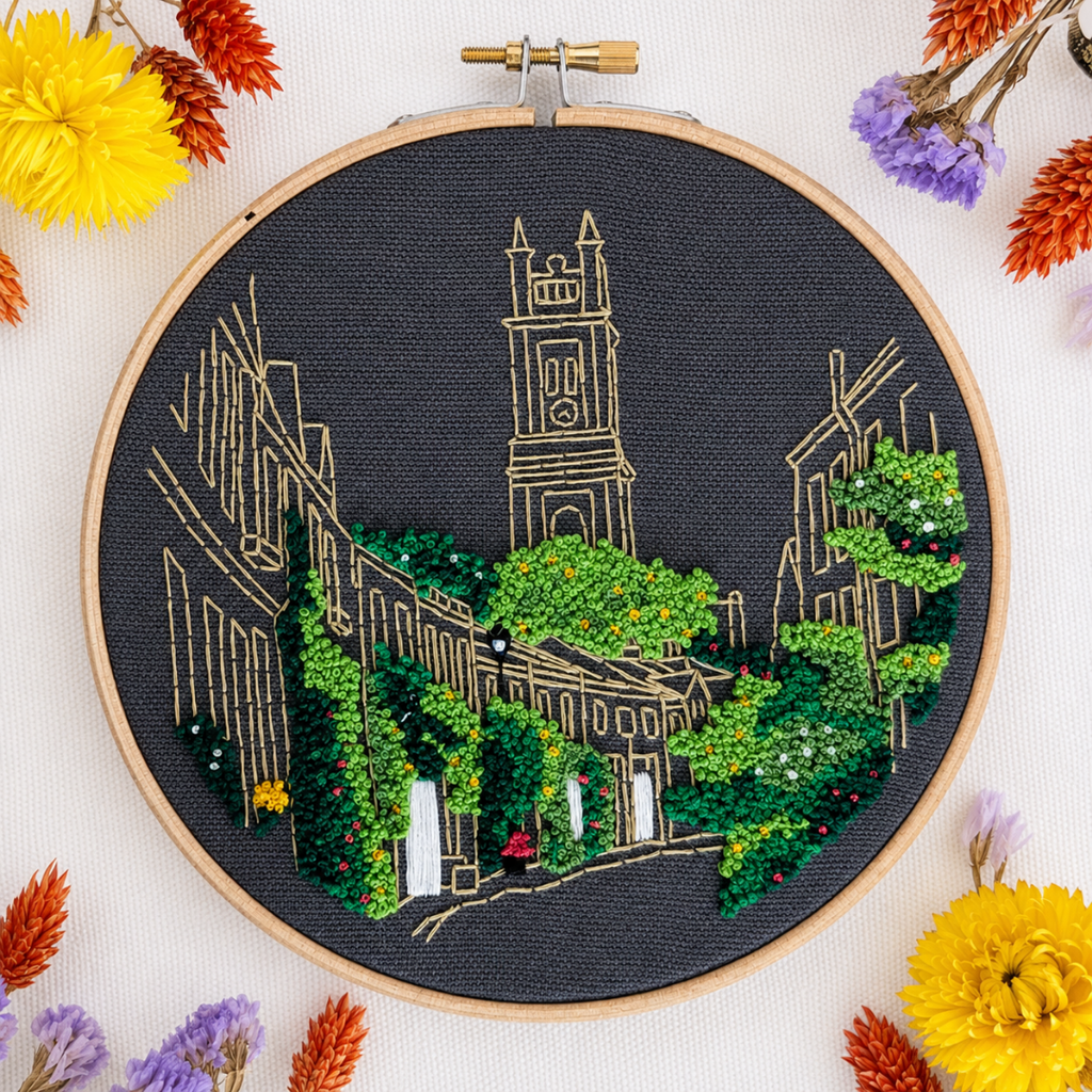 Finished Circus Lane embroidery displayed with colourful threads and flowers.