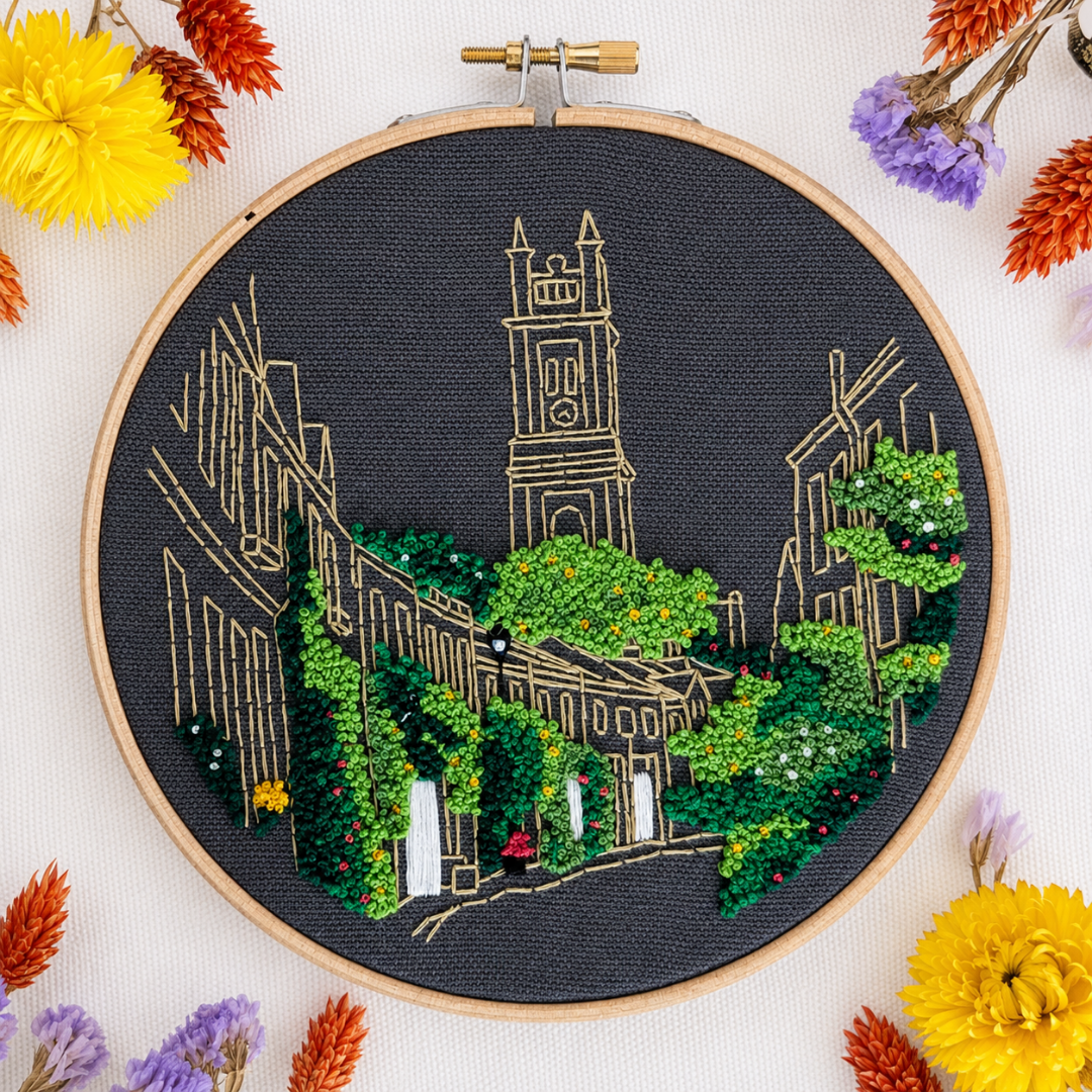 Finished Circus Lane embroidery displayed with colourful threads and flowers.