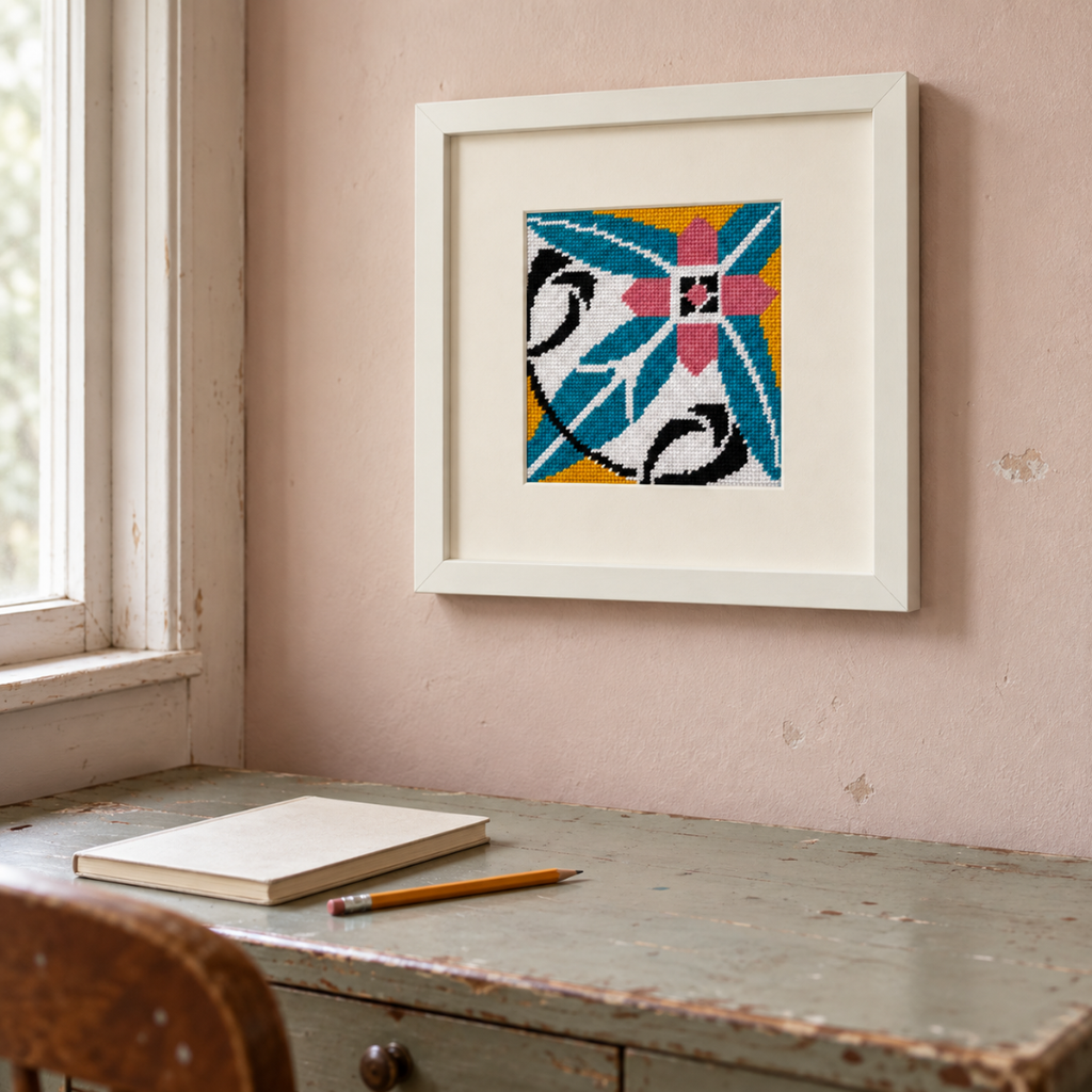 Finished Costa Cabral Portuguese tile needlepoint displayed in a cream frame on a wooden desk.