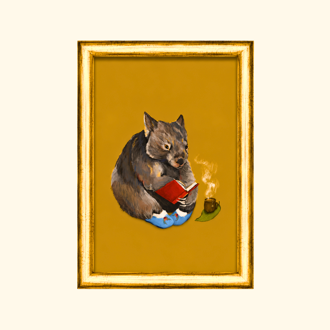 Cosy Wombat greeting card displayed in an A6 gold frame, showcasing the whimsical wombat illustration on a warm mustard background.