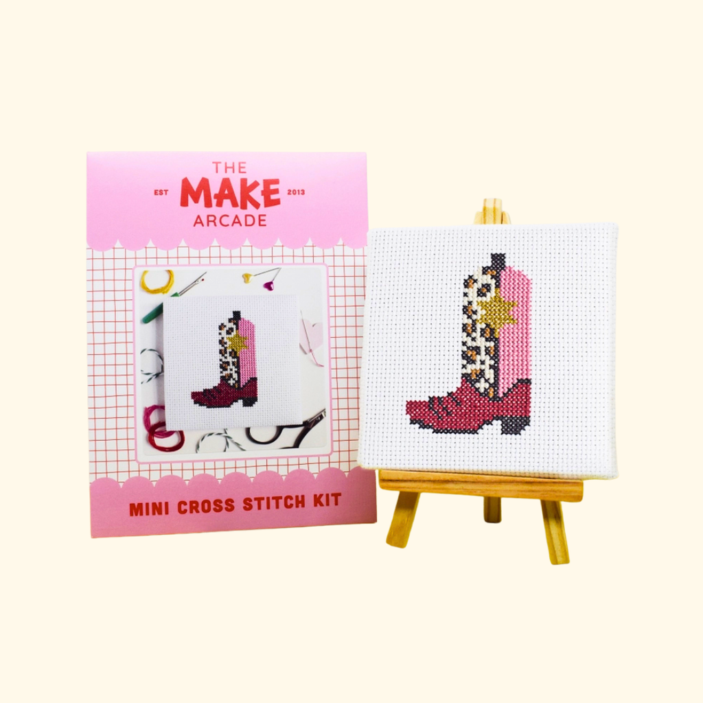 Cowgirl Boot Mini Cross Stitch Kit by The Make Arcade with packaging and finished stitched design on a mini easel.