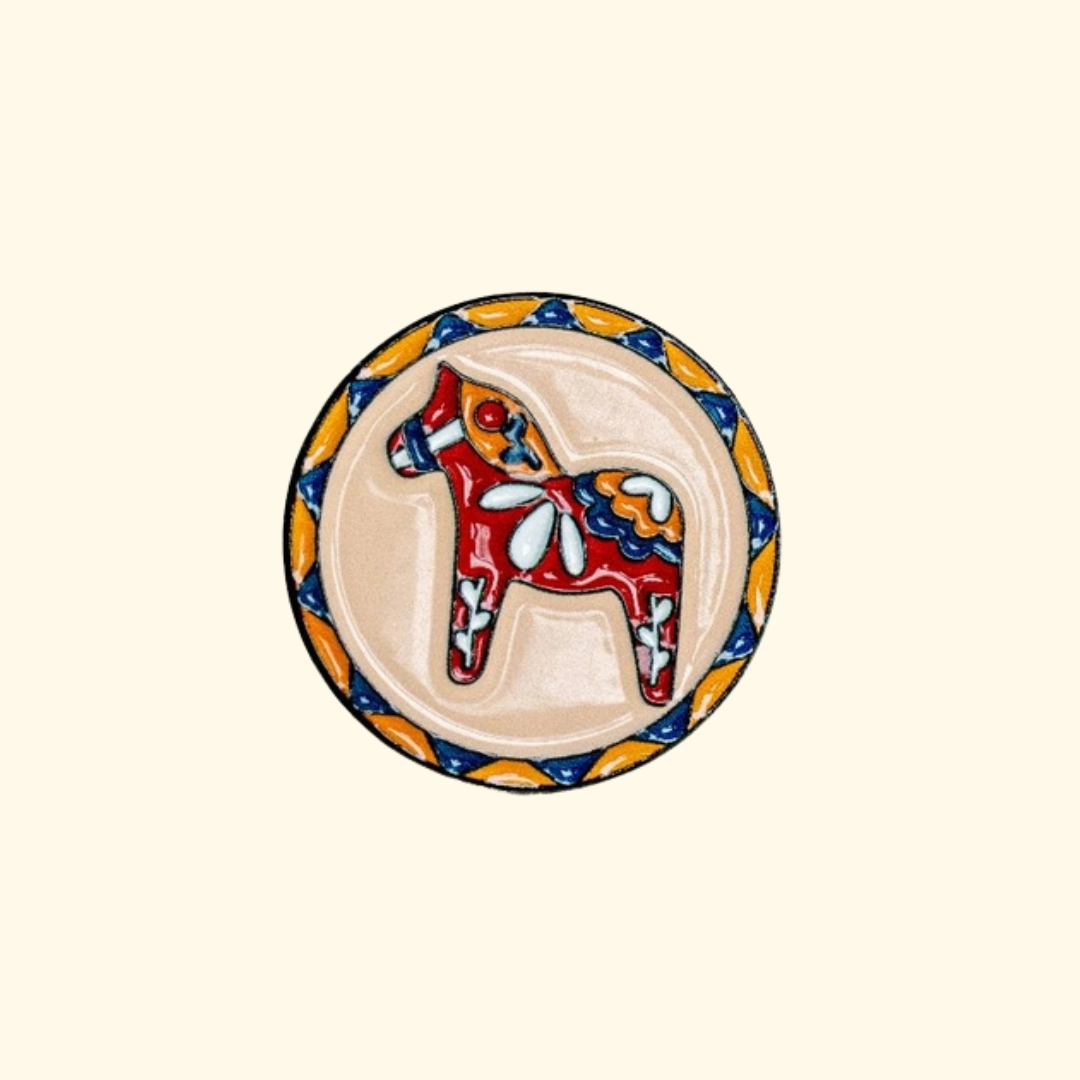 Colourful enamel Dala horse magnetic needle minder by Unwind Studio on a cream background.