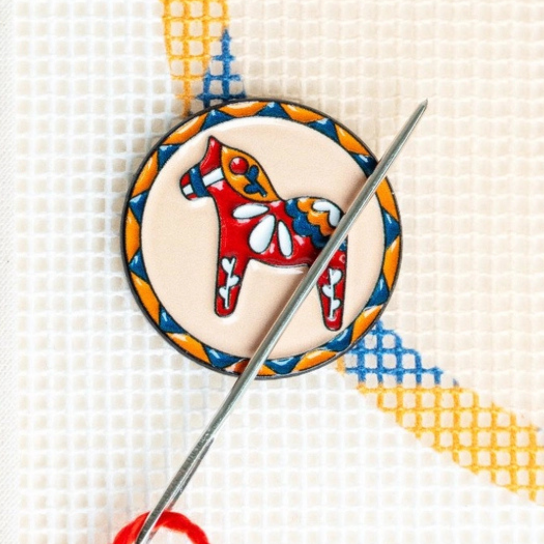 Dala Horse Magnetic Needle Minder holding a needle on a needlepoint canvas during stitching.