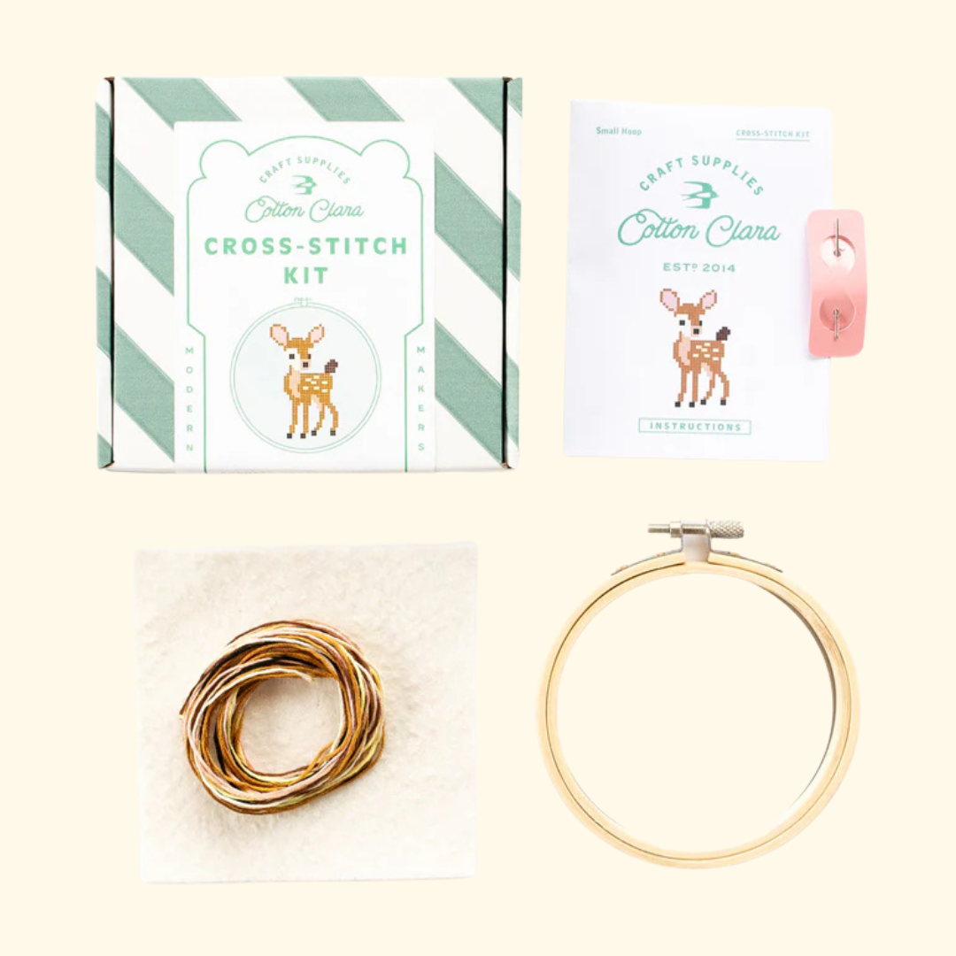 Contents of the Cotton Clara Deer Cross Stitch Kit including hoop, fabric, threads, needle and instructions.
