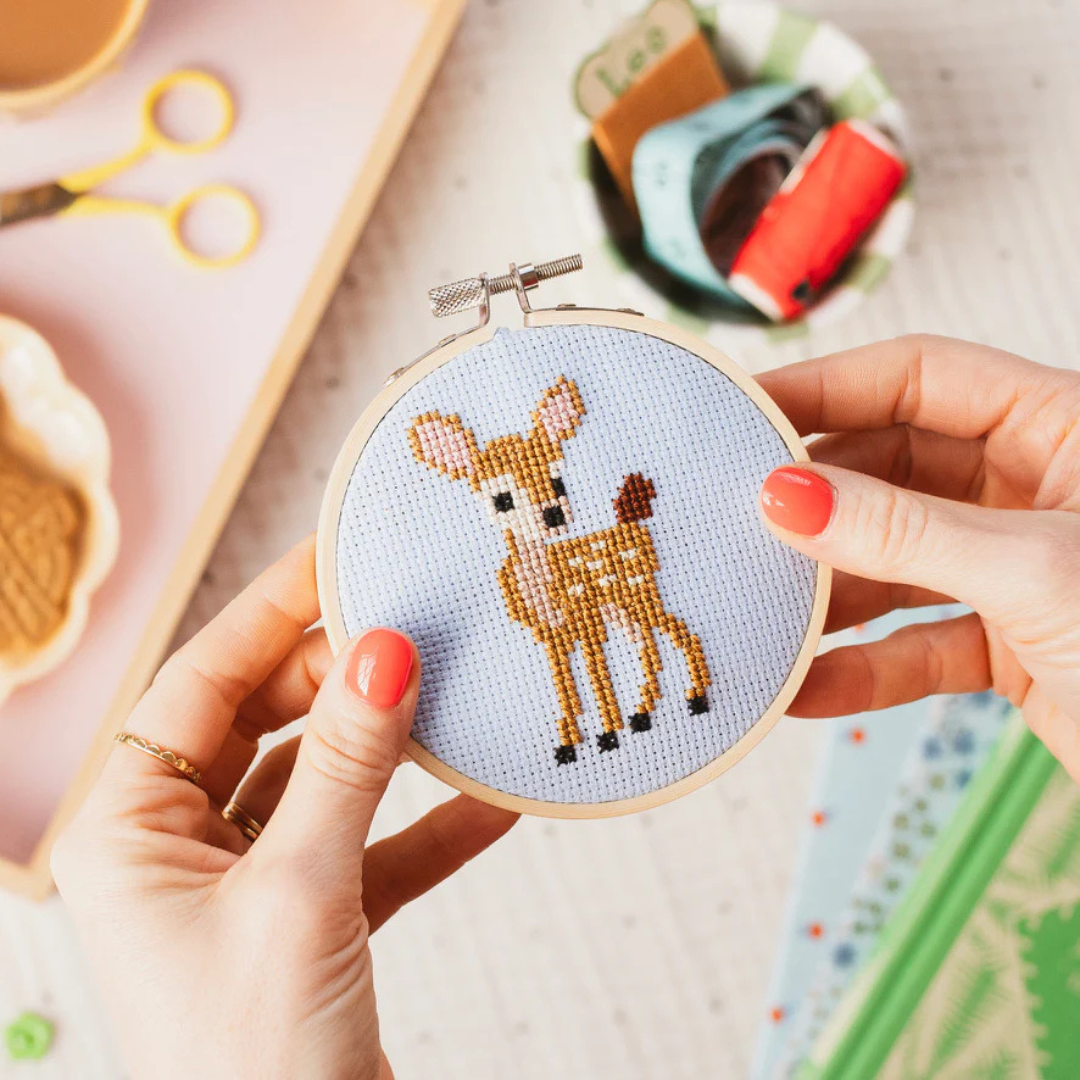 Hands stitching the deer cross stitch design using the Cotton Clara craft kit.