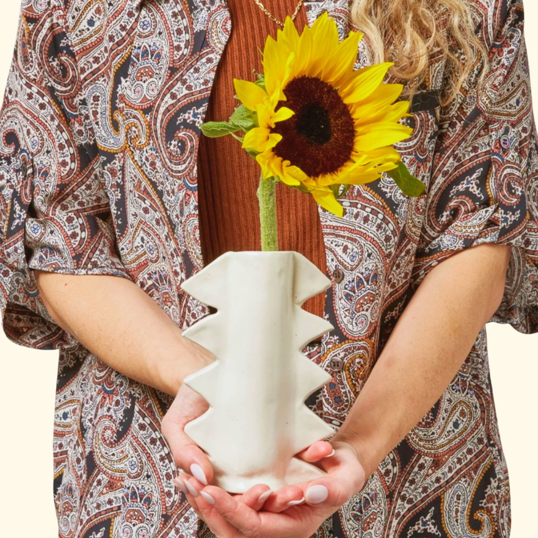 Person holding completed handmade white clay vase with zigzag design