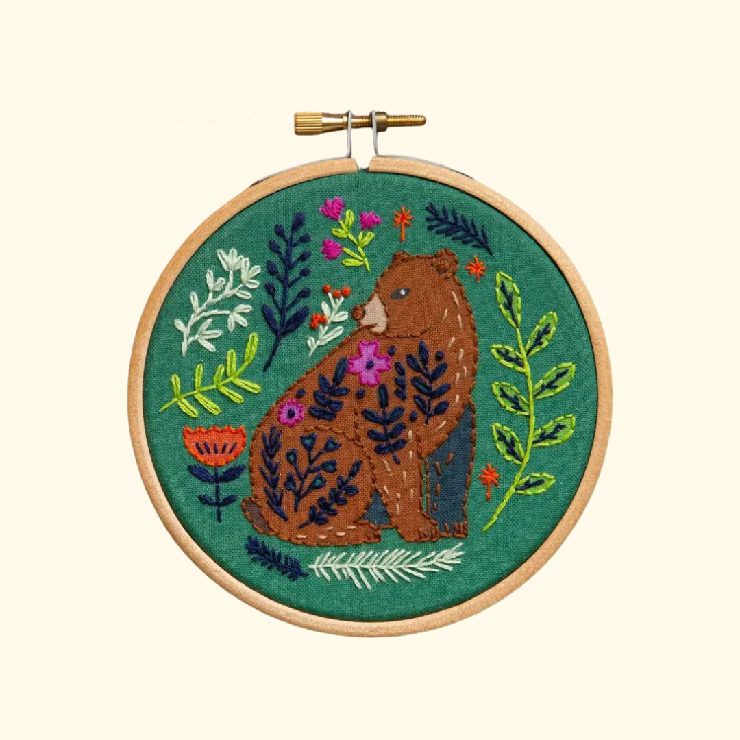 Finished Folk Bear Mini Embroidery Kit featuring a brown bear surrounded by colourful flowers and foliage in a wooden embroidery hoop.