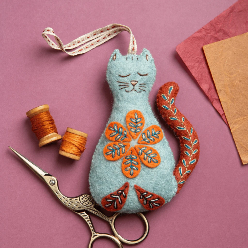Folk Cat felt craft kit by Corinne Lapierre displayed with sewing tools and embroidery materials.