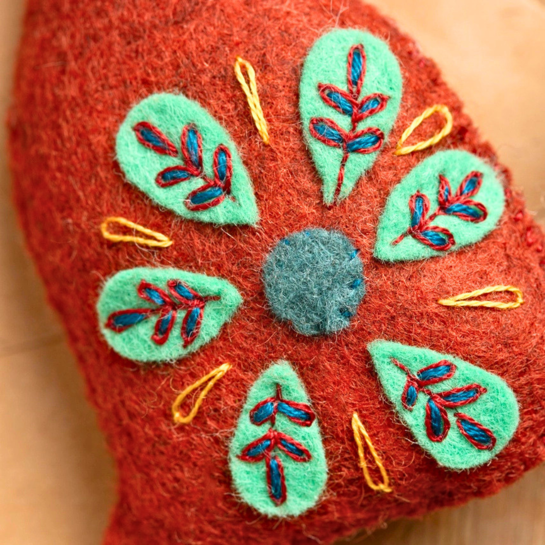 Close-up of colourful floral and leaf embroidery on the burnt orange felt dog.