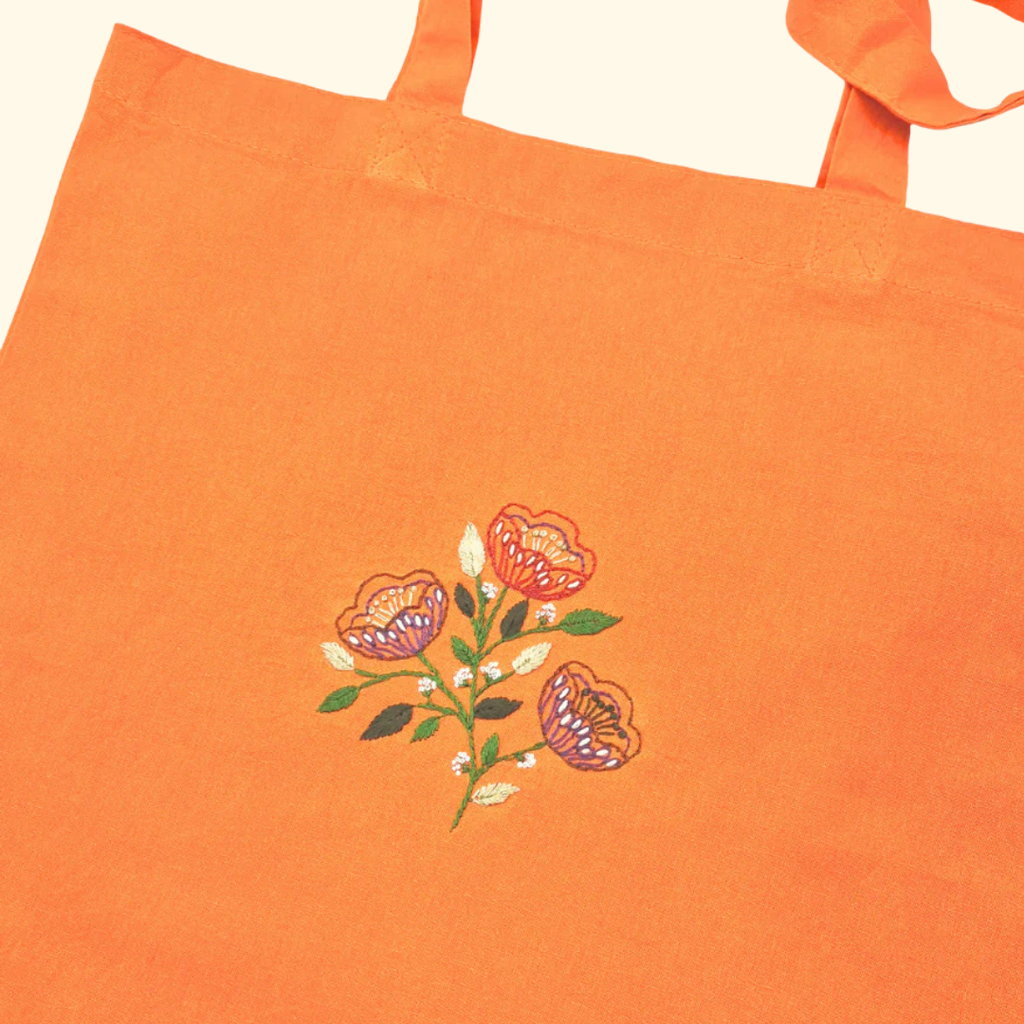 Orange tote bag embroidered with colourful folk flower design using stick and stitch transfers