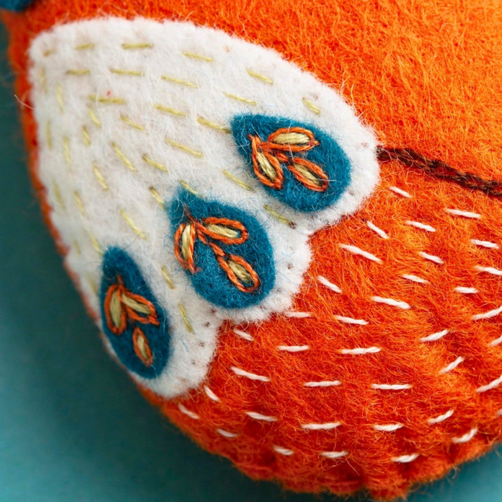 Close-up of the orange felt fox showing white tail detail and colourful folk-inspired embroidery.