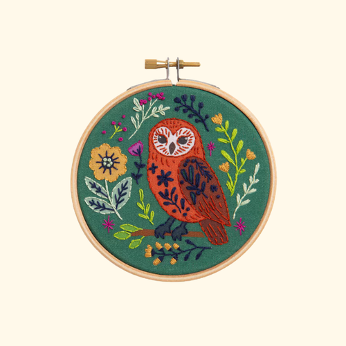 Finished folk owl embroidery displayed in a wooden hoop on a plain cream background.