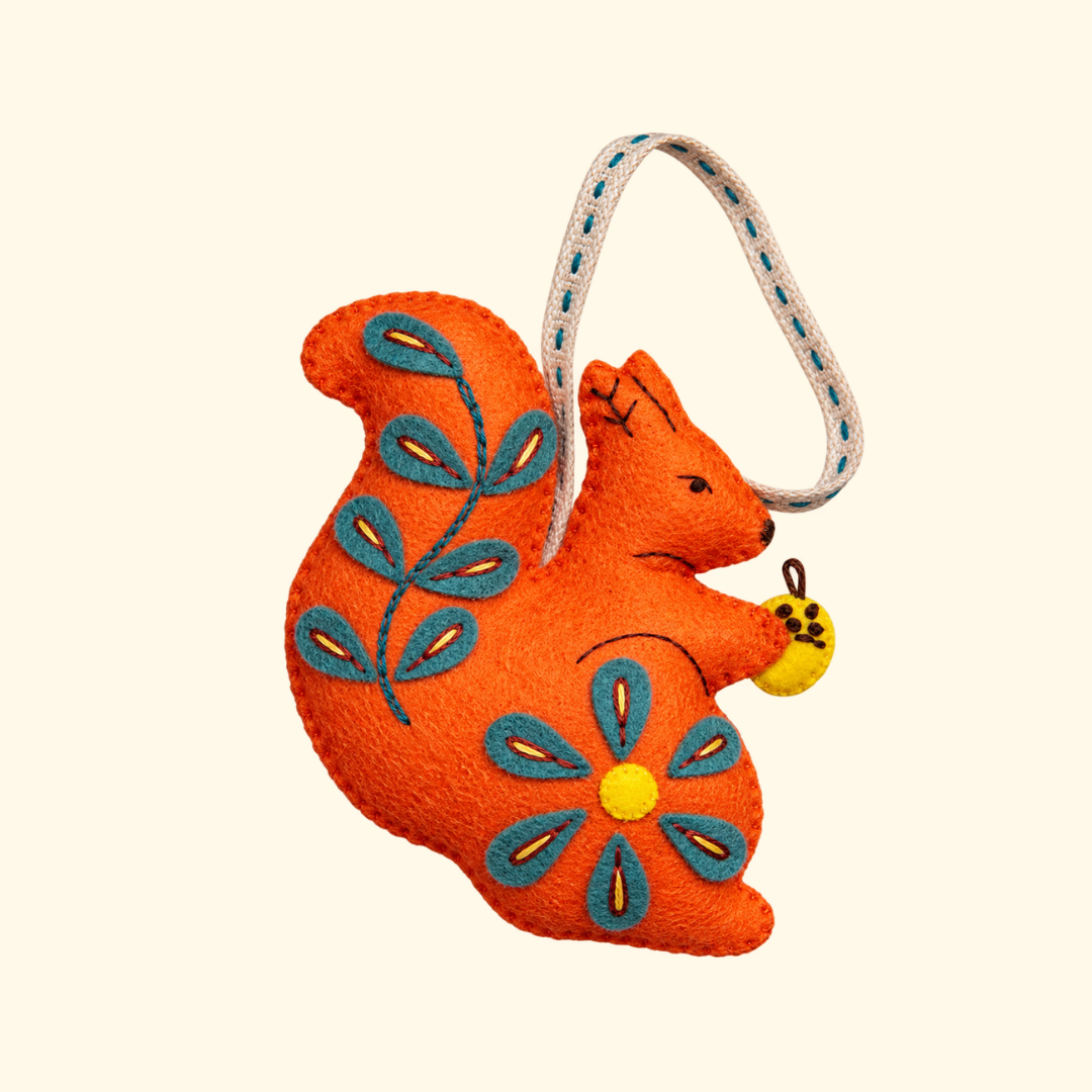 Completed orange felt squirrel ornament with blue and yellow floral embroidery and hanging loop.