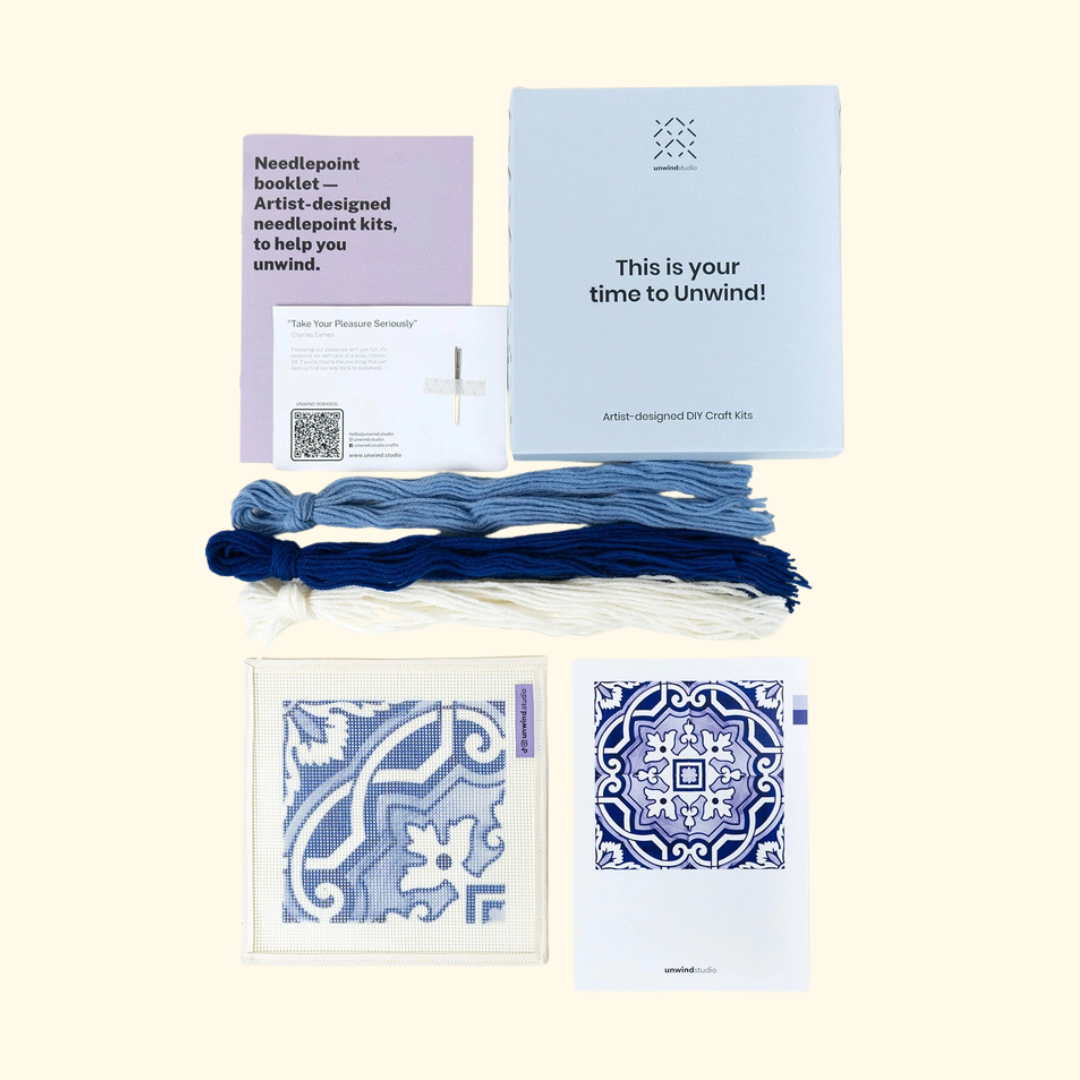Fontainhas needlepoint kit contents with printed canvas, blue threads, needles, instructions and colour guide.