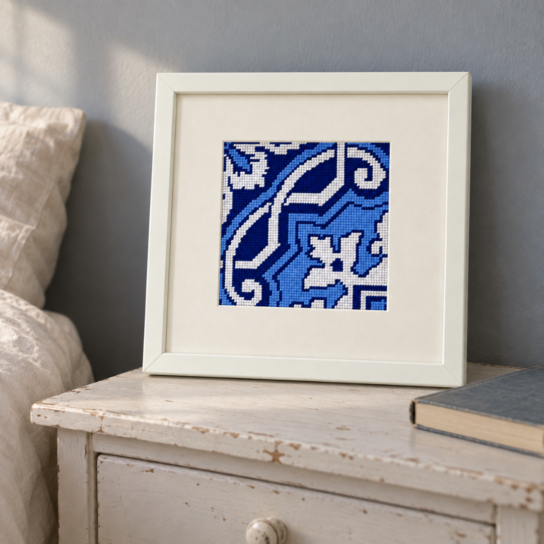 Finished Fontainhas Portuguese tile needlepoint displayed in a cream frame on a vintage wooden table.