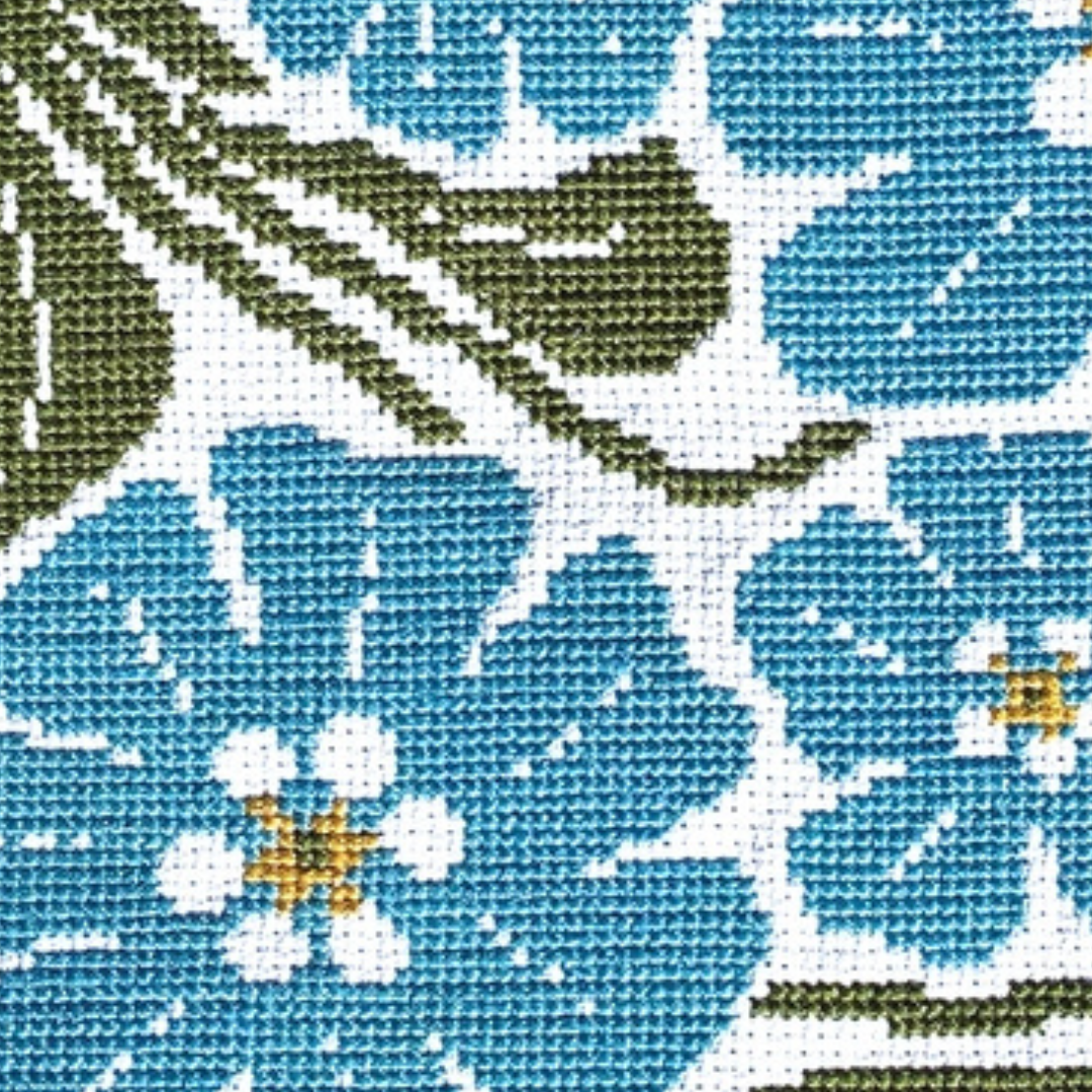 Close-up of the Forget Me Not Grid cross stitch design showing blue flowers, white centres and green leaves.