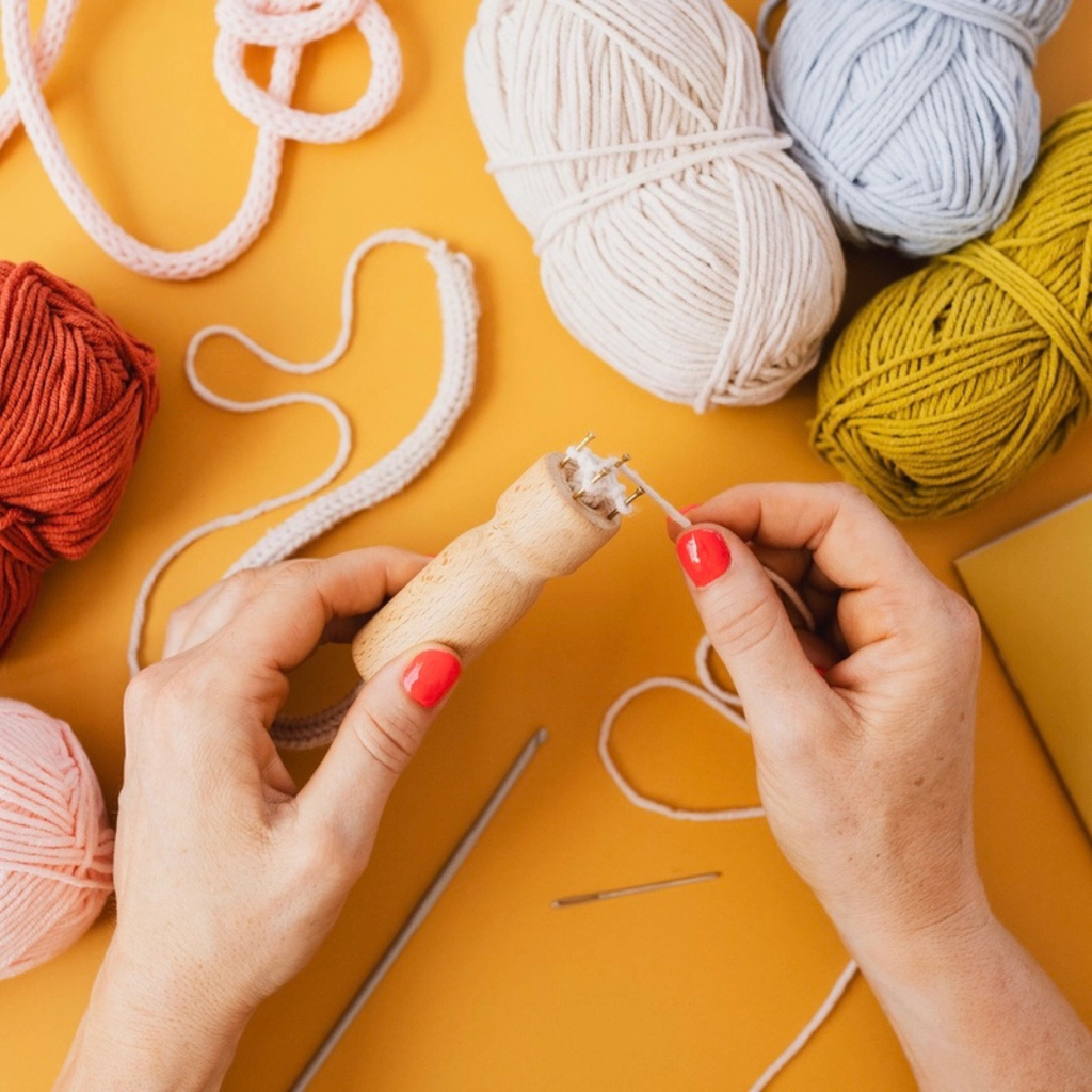 Hands using the French knitting tool with colourful yarn from the Cotton Clara kit.