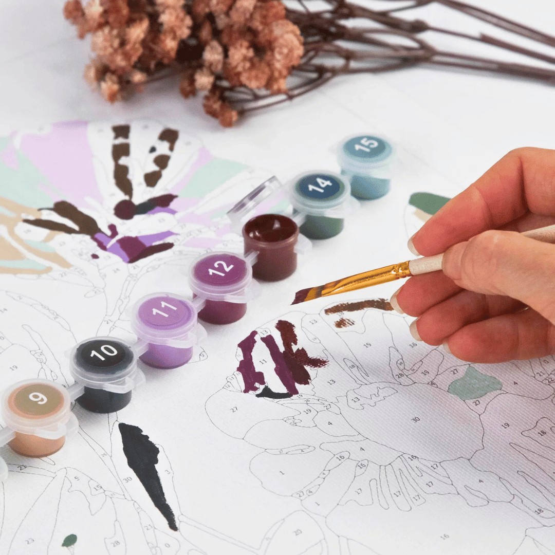 Close-up of the Greenscapes Paint by Numbers Kit by Journey of Something showing an adult painting the floral artwork with the included acrylic paints.