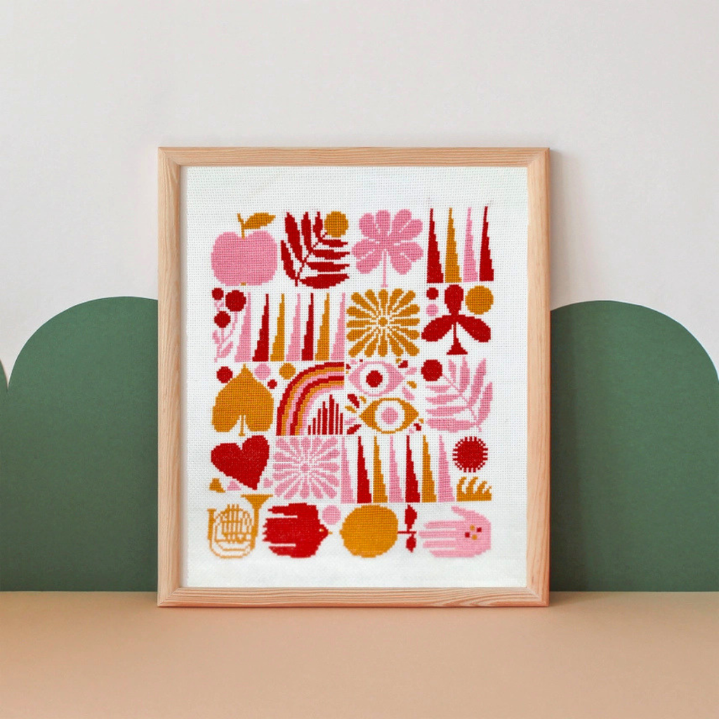 Framed Harvest Grid cross stitch displayed on a shelf in a modern home setting with a soft green backdrop.