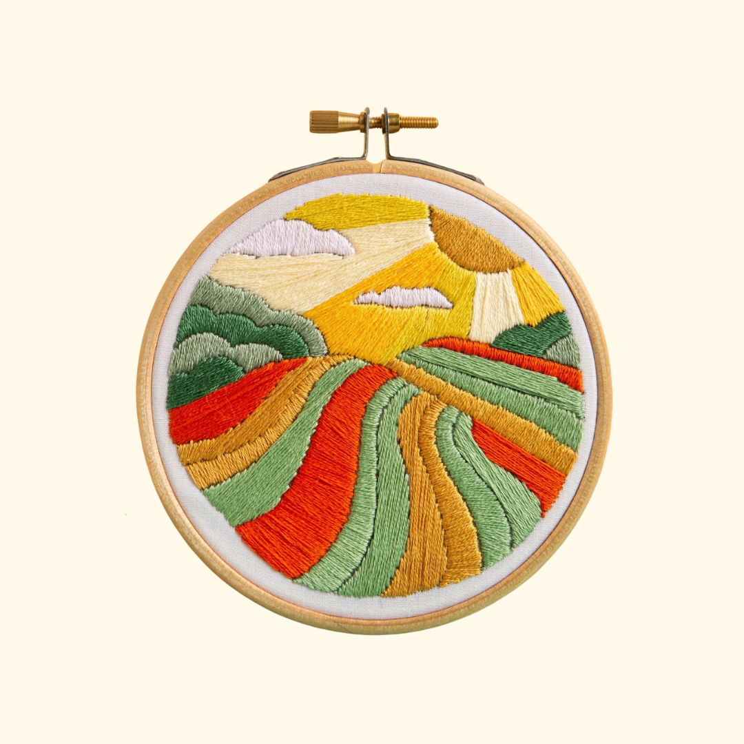 Harvest Time Mini Embroidery Kit by Hawthorn Handmade featuring colourful rolling fields, patchwork farmland and a golden countryside landscape.